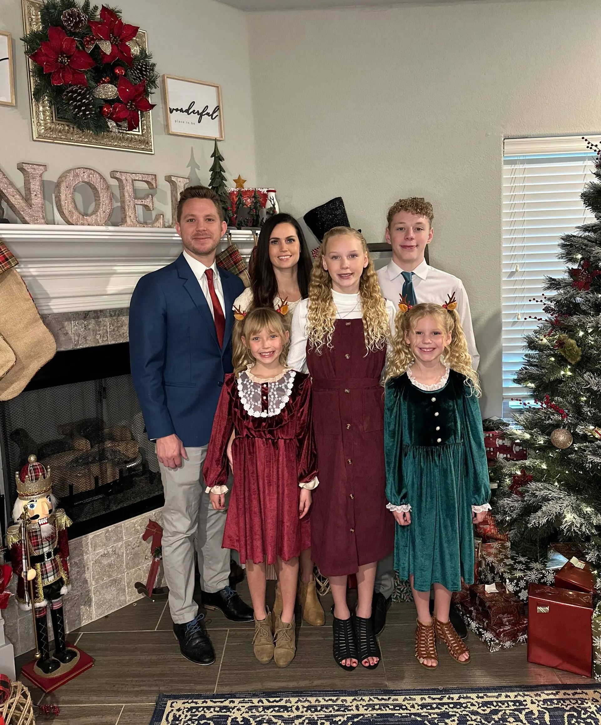 Jessica, Superhost of A Still Point Cabin, with her husband and their four children in front of the fireplace at Christmas